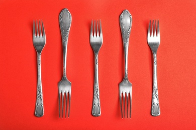 Photo of Vintage silver forks on red background, flat lay