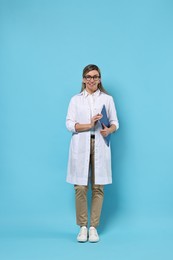Photo of Portrait of happy doctor with clipboard on light blue background