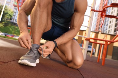 Man tying shoelaces before training at outdoor gym, closeup