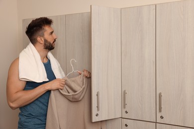 Photo of Handsome man taking clothes from locker in changing room