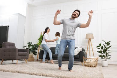 Photo of Happy family dancing and having fun in living room, low angle view