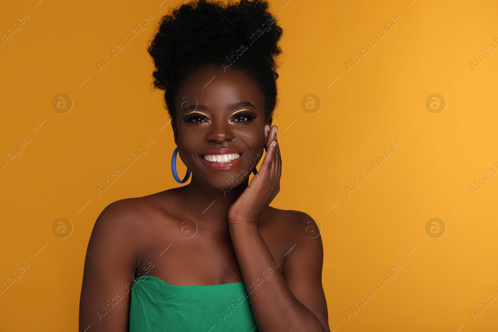 Photo of Fashionable portrait of beautiful happy woman with makeup on orange background, space for text