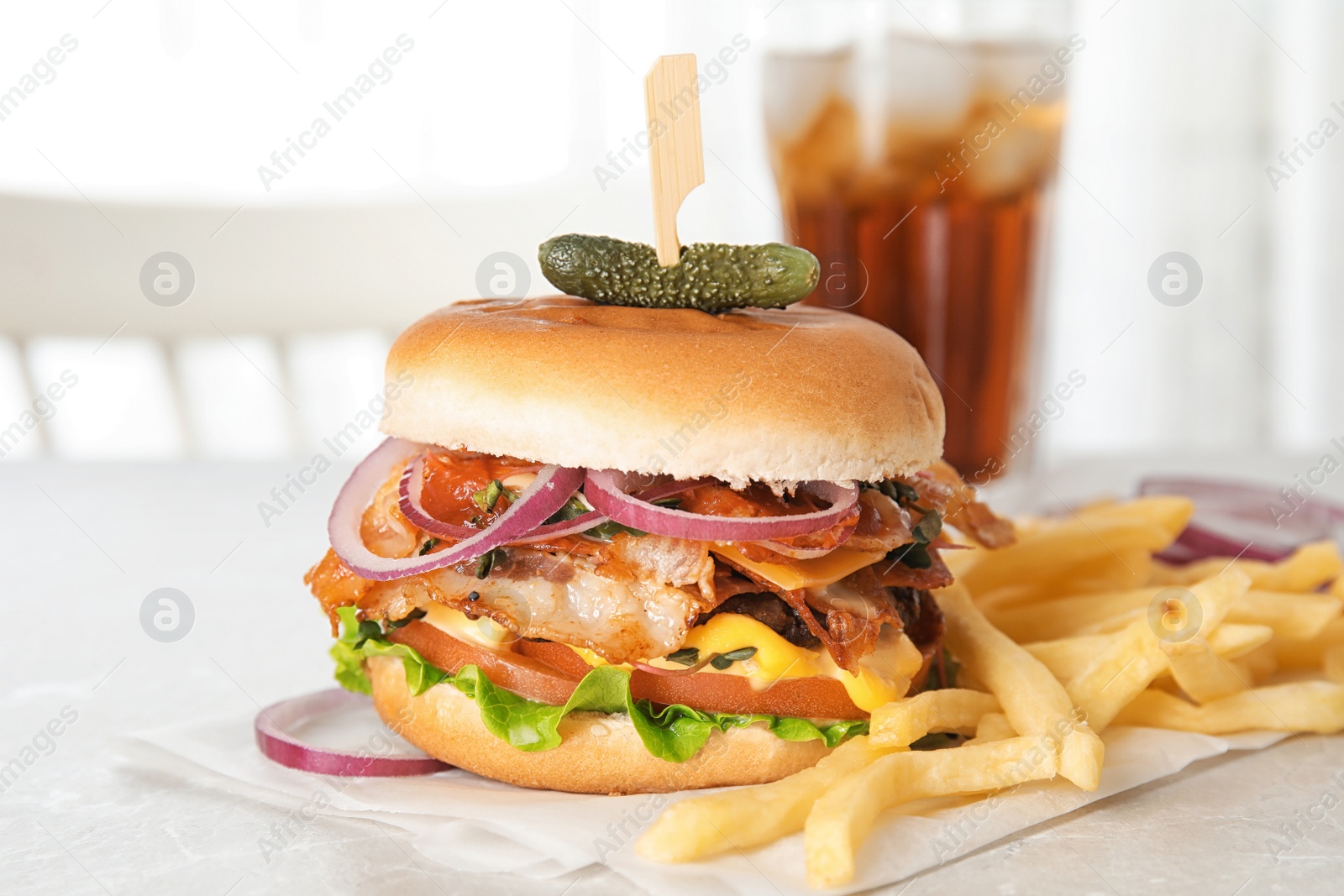 Photo of Tasty burger with bacon and French fries on table