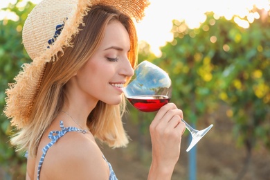 Young beautiful woman enjoying wine at vineyard