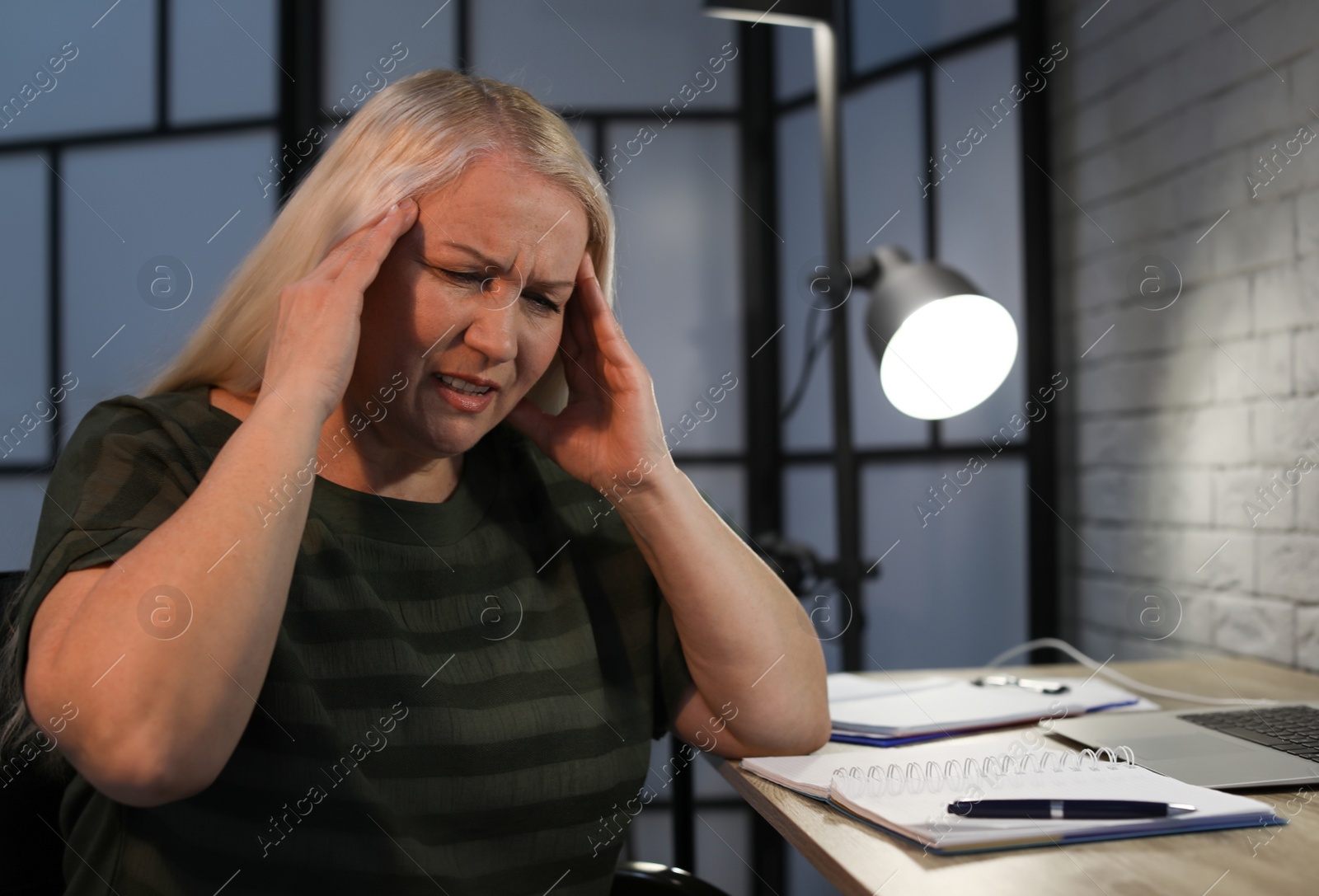 Photo of Overworked mature woman with headache in office