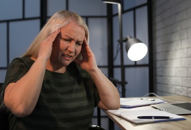 Overworked mature woman with headache in office