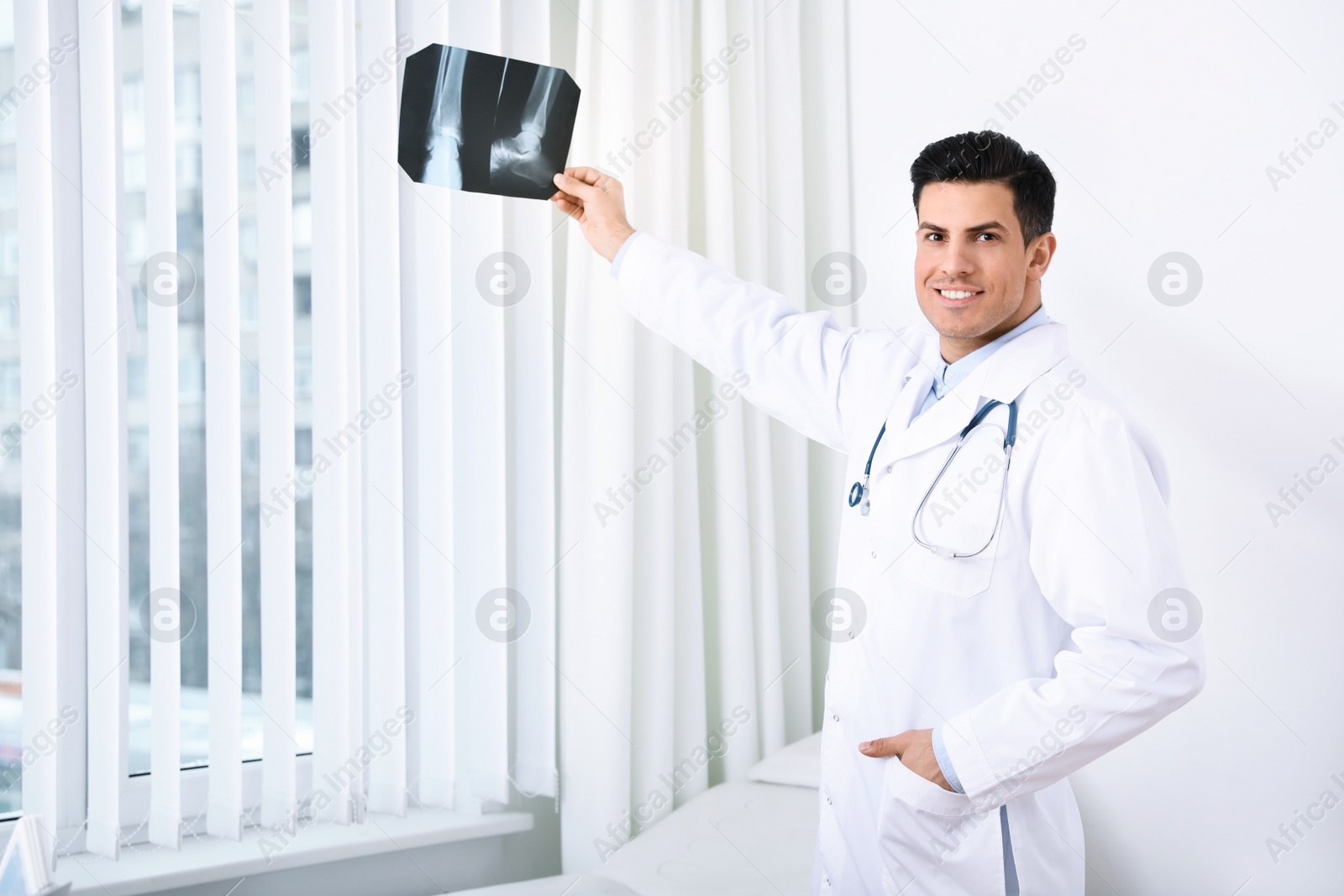 Photo of Orthopedist examining X-ray picture near window in office