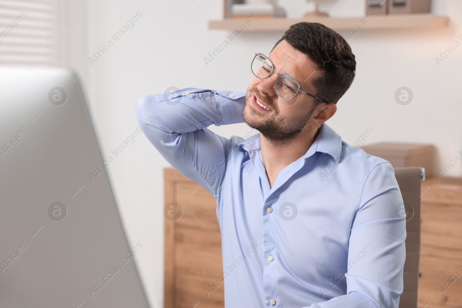 Photo of Man suffering from neck pain in office