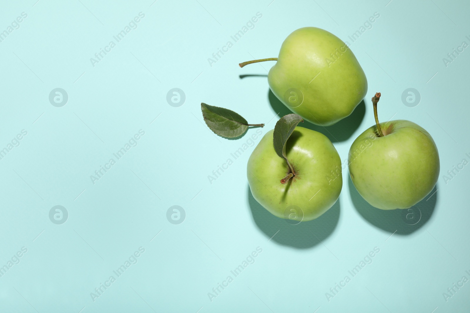 Photo of Fresh green apples on light blue background, flat lay. Space for text