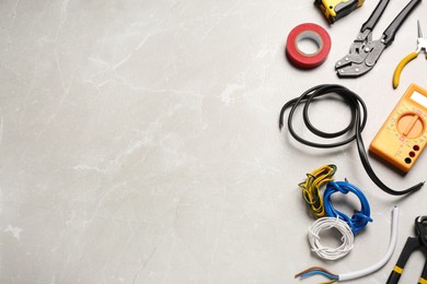 Photo of Different wires and electrical tools on light grey marble table, flat lay. Space for text