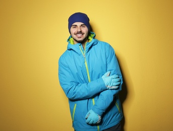 Young man wearing warm clothes on color background, space for text. Ready for winter vacation