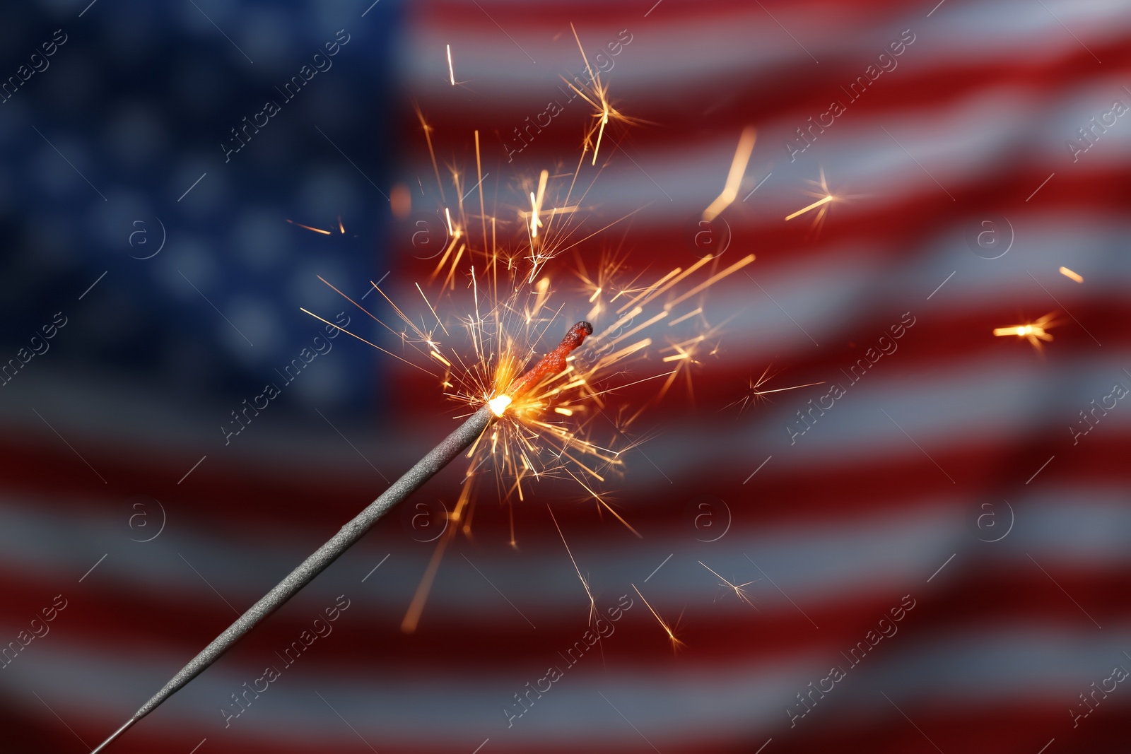 Photo of Burning sparkler against USA flag, closeup. Happy Independence Day