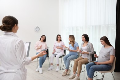 Group of pregnant women with doctor at courses for expectant mothers indoors