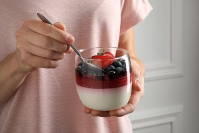 Photo of Woman eating delicious panna cotta with berries, closeup