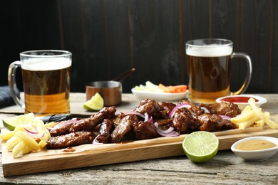 Tasty roasted chicken wings served with beer on wooden table, closeup