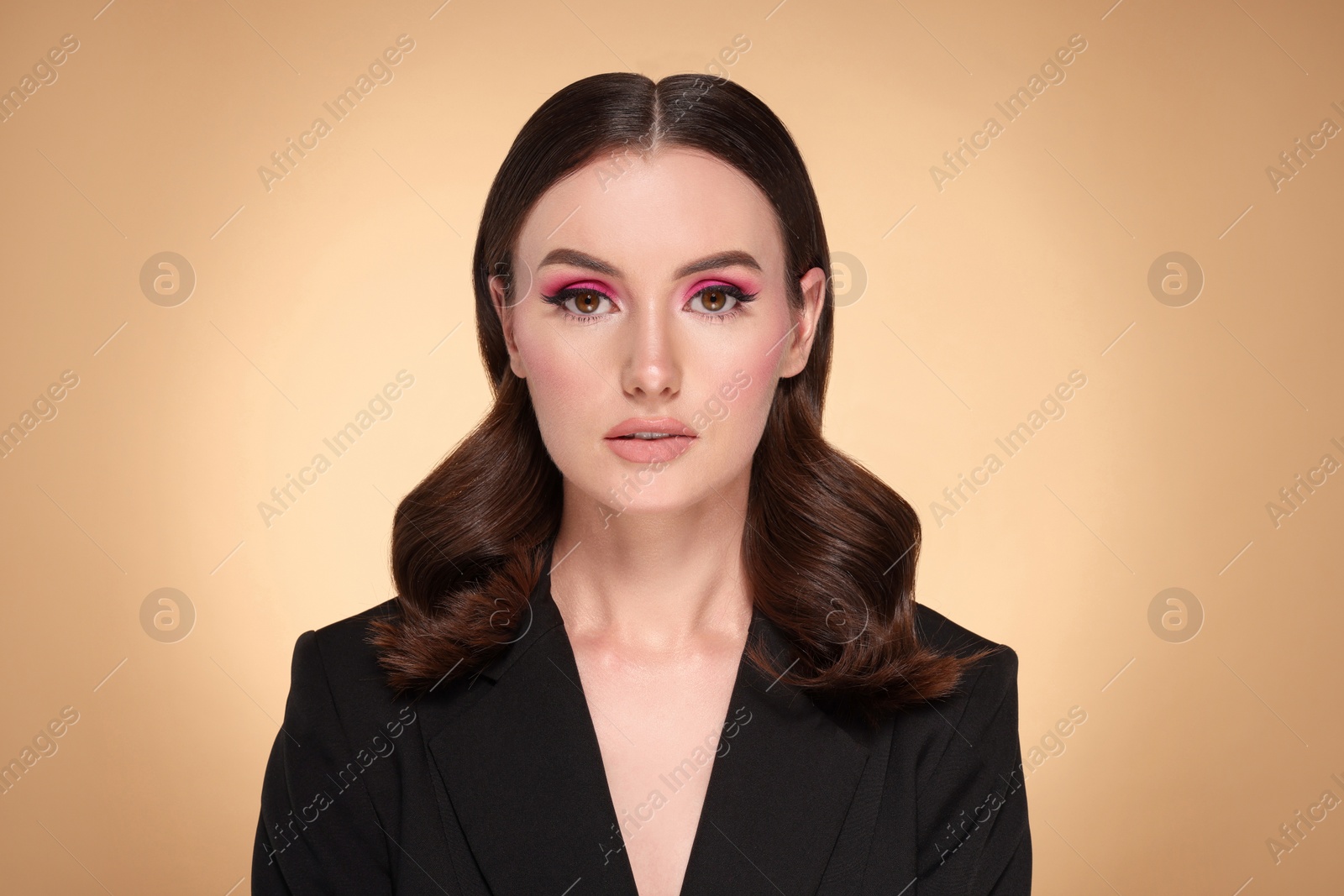 Photo of Portrait of beautiful young woman with makeup and gorgeous hair styling on beige background