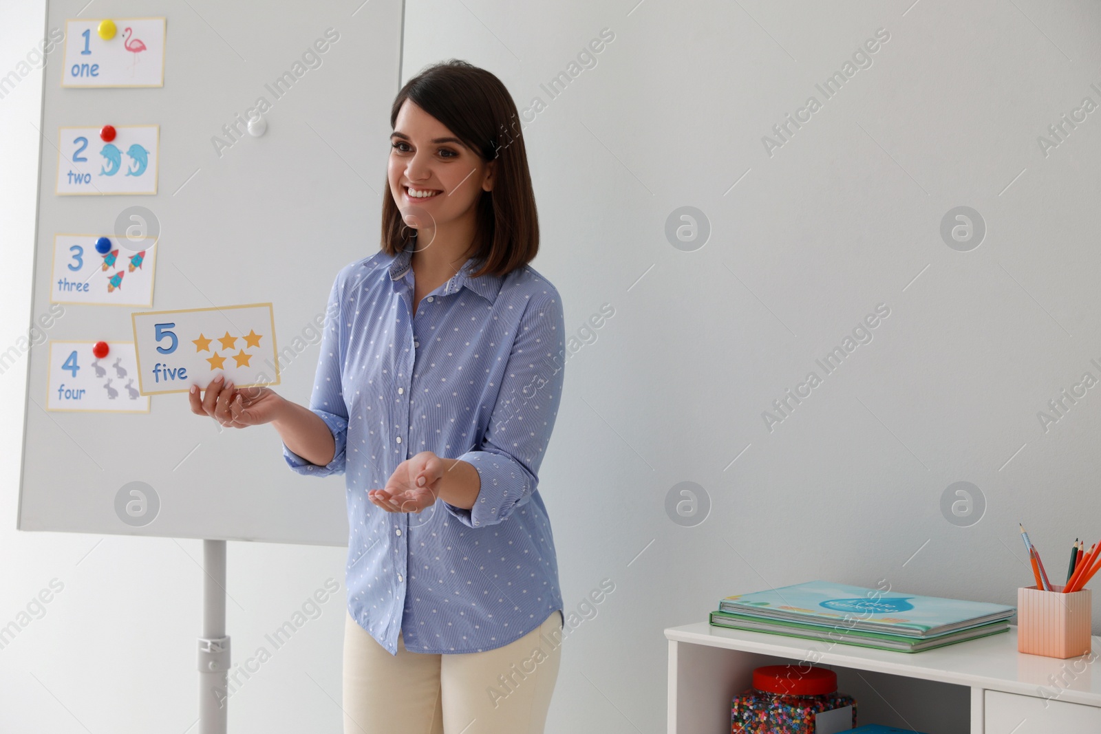 Photo of Happy female English teacher giving lesson indoors. Early childhood education