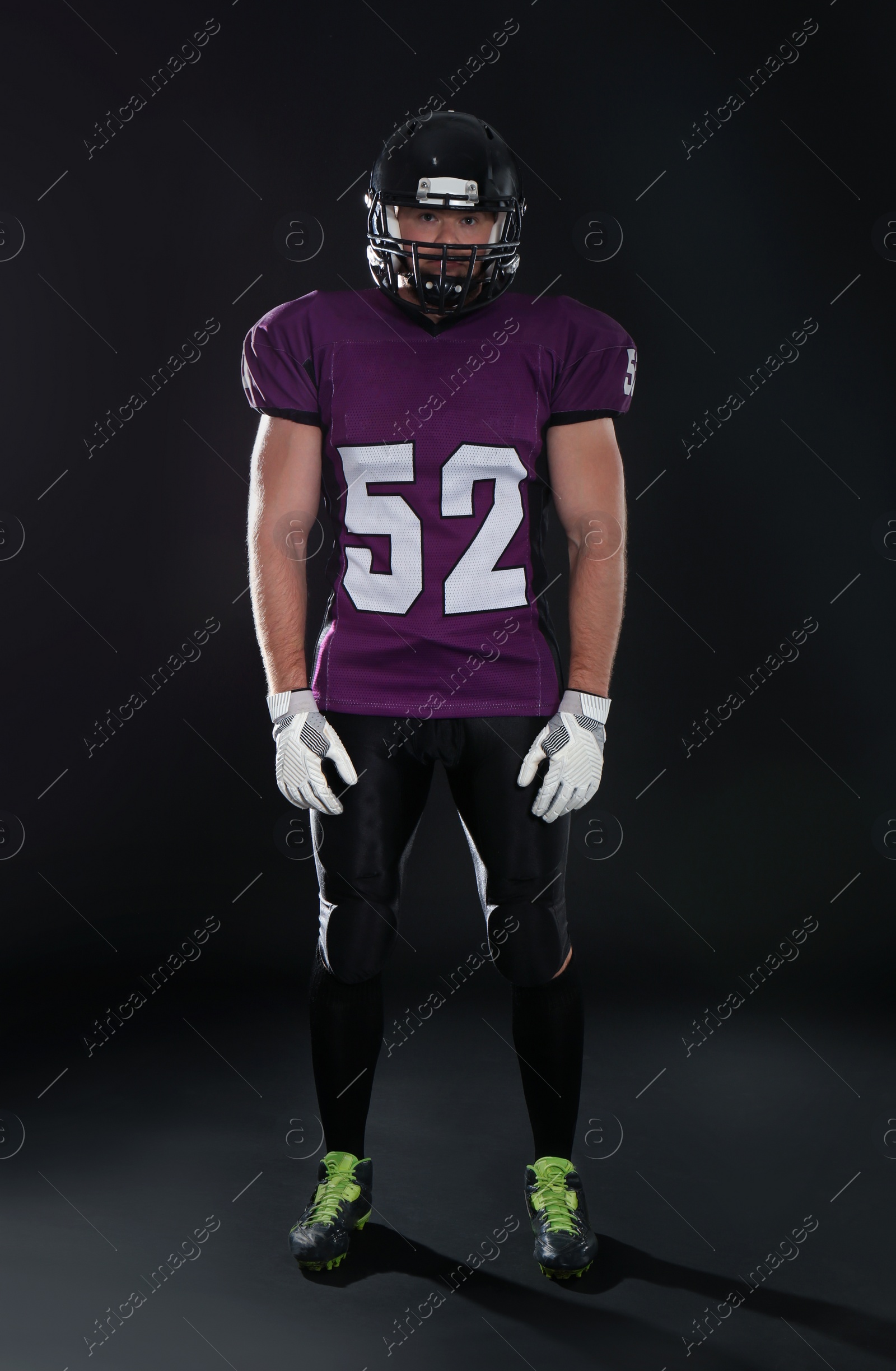 Photo of American football player wearing uniform on dark background