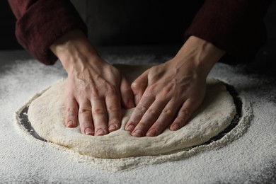 Photo of Woman kneading pizza dough at table, closeup