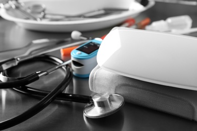 Photo of Sphygmomanometer, stethoscope and blood pressure monitor on grey table. Medical objects