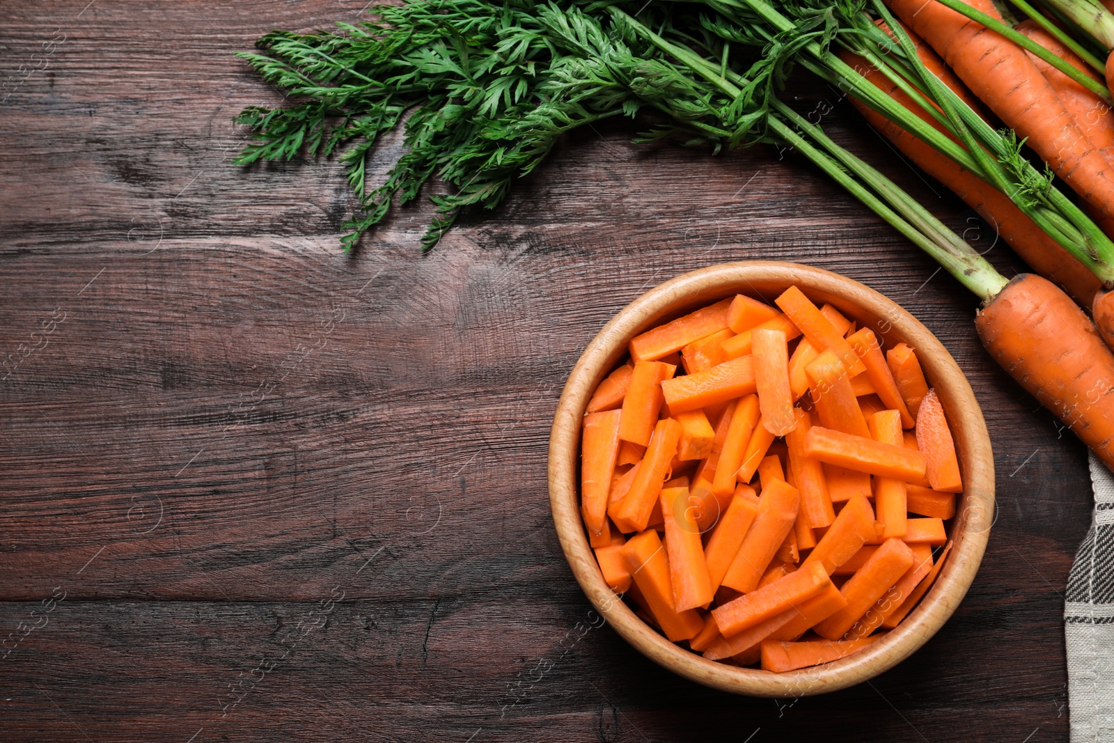 Photo of Whole and cut ripe carrots on brown wooden table, flat lay. Space for text