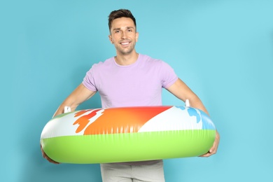 Photo of Happy young man with bright inflatable ring on blue background