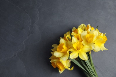 Bouquet of daffodils on dark background, top view with space for text. Fresh spring flowers