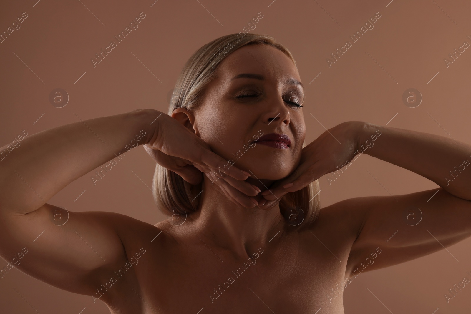 Photo of Beautiful woman touching her neck on beige background