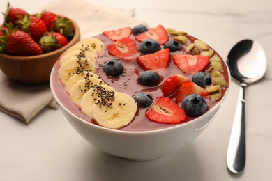 Photo of Bowl of delicious smoothie with fresh blueberries, strawberries, banana and pumpkin seeds on white table, closeup