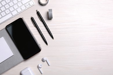 Flat lay composition with mobile phone on wooden table. Space for text