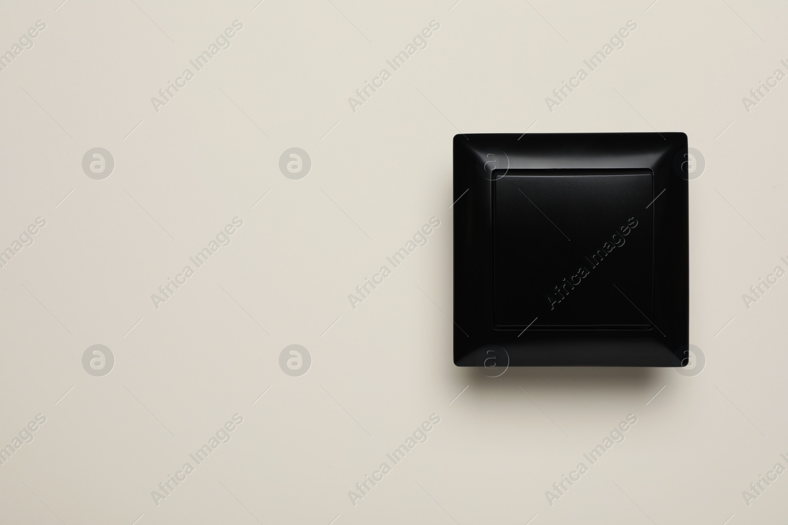 Photo of Black light switch on beige background, top view. Space for text