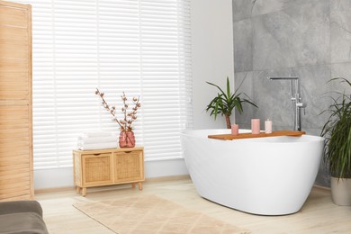 Photo of Stylish bathroom interior with beautiful tub, houseplants and decor elements