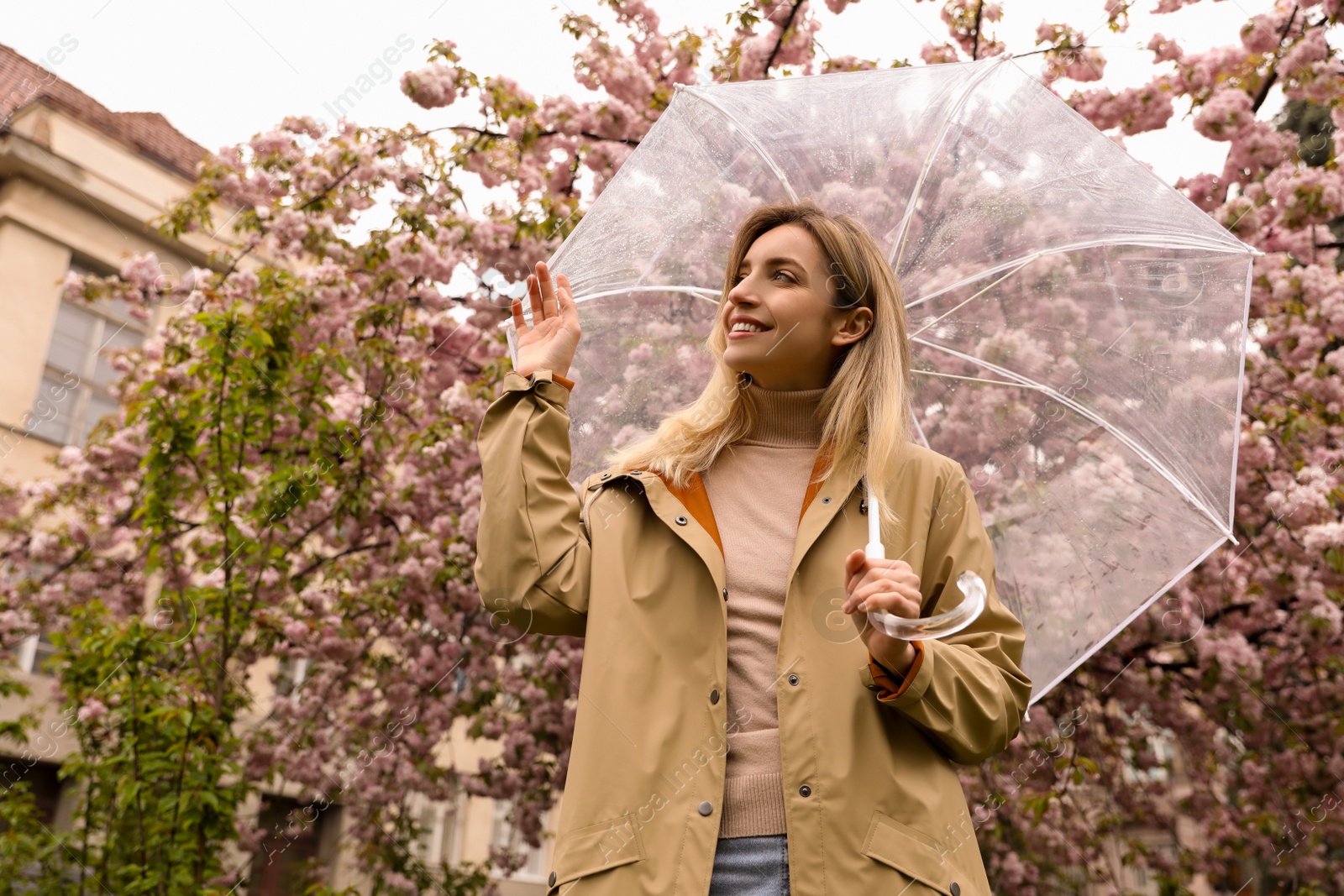 Photo of Young woman with umbrella near blossoming tree on spring day