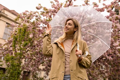 Photo of Young woman with umbrella near blossoming tree on spring day