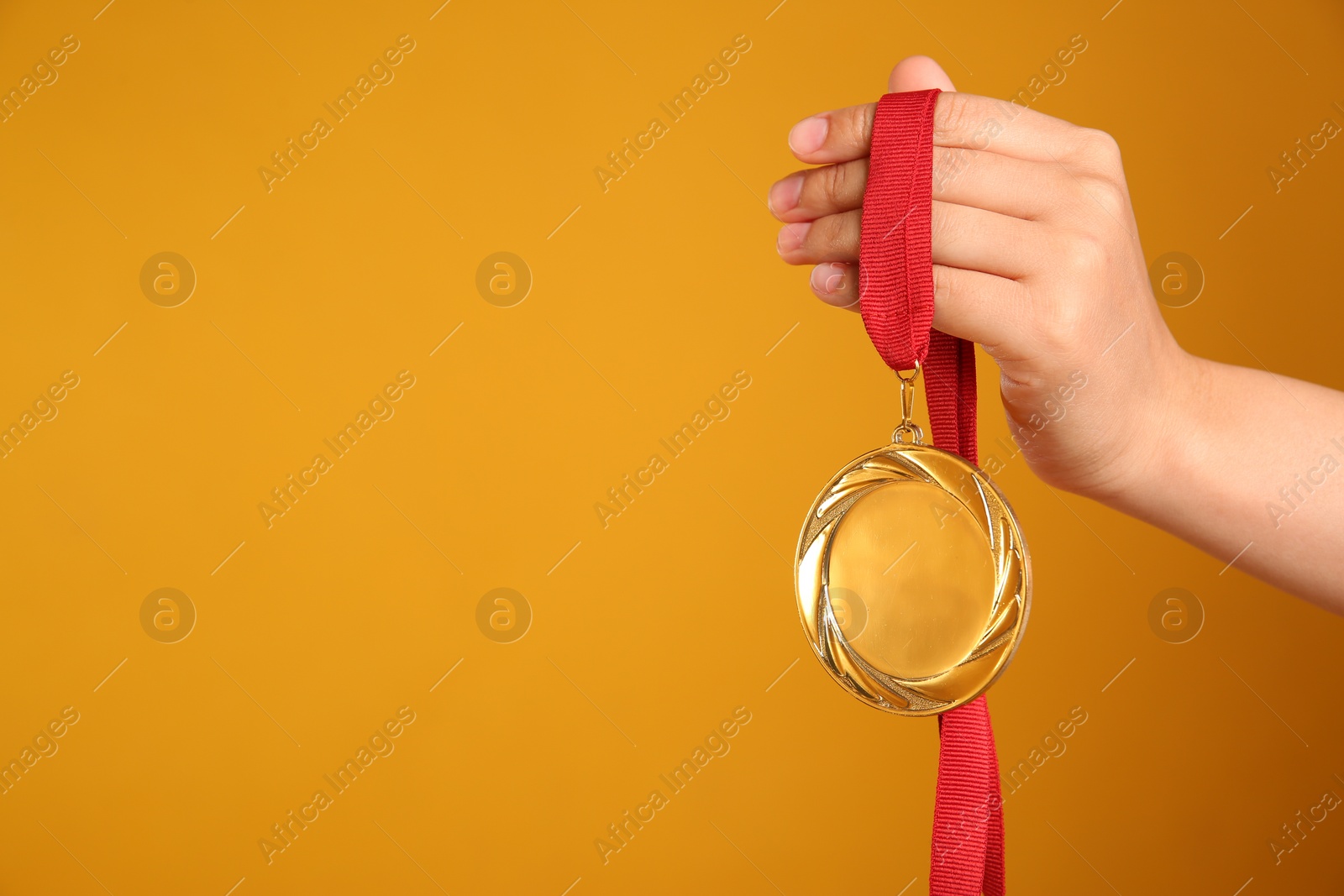 Photo of Woman holding gold medal on yellow background, closeup. Space for text