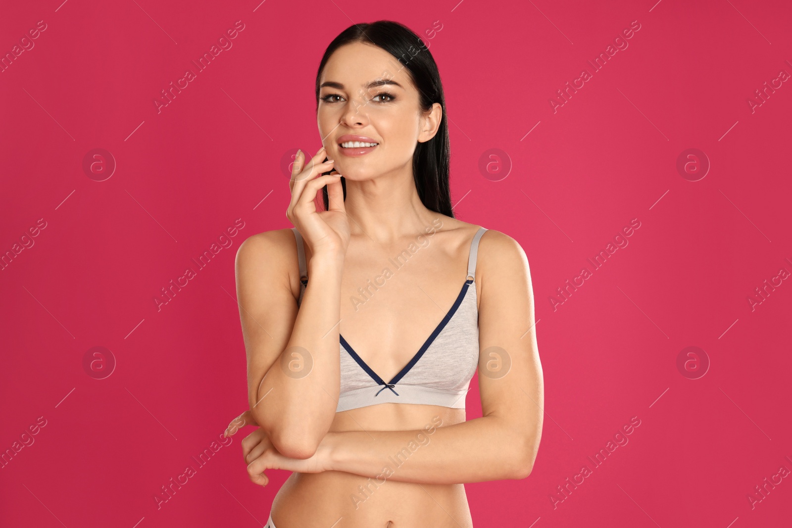 Photo of Beautiful young woman in grey sportive underwear on pink background