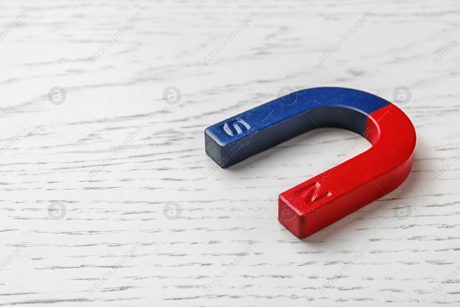 Photo of Red and blue horseshoe magnet on wooden background. Space for text