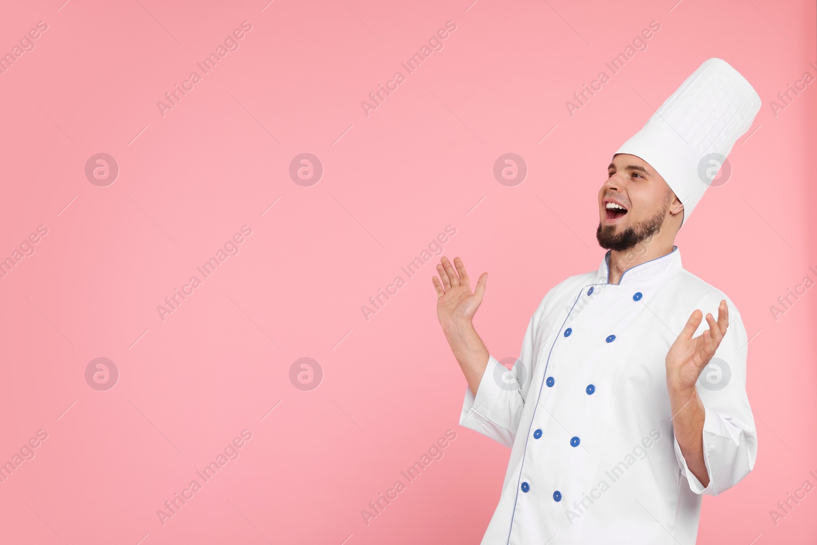 Photo of Excited professional confectioner in uniform on pink background. Space for text