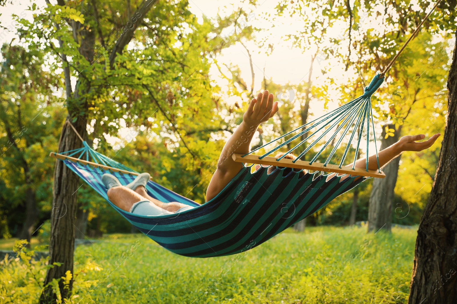 Photo of Young man resting in comfortable hammock at green garden