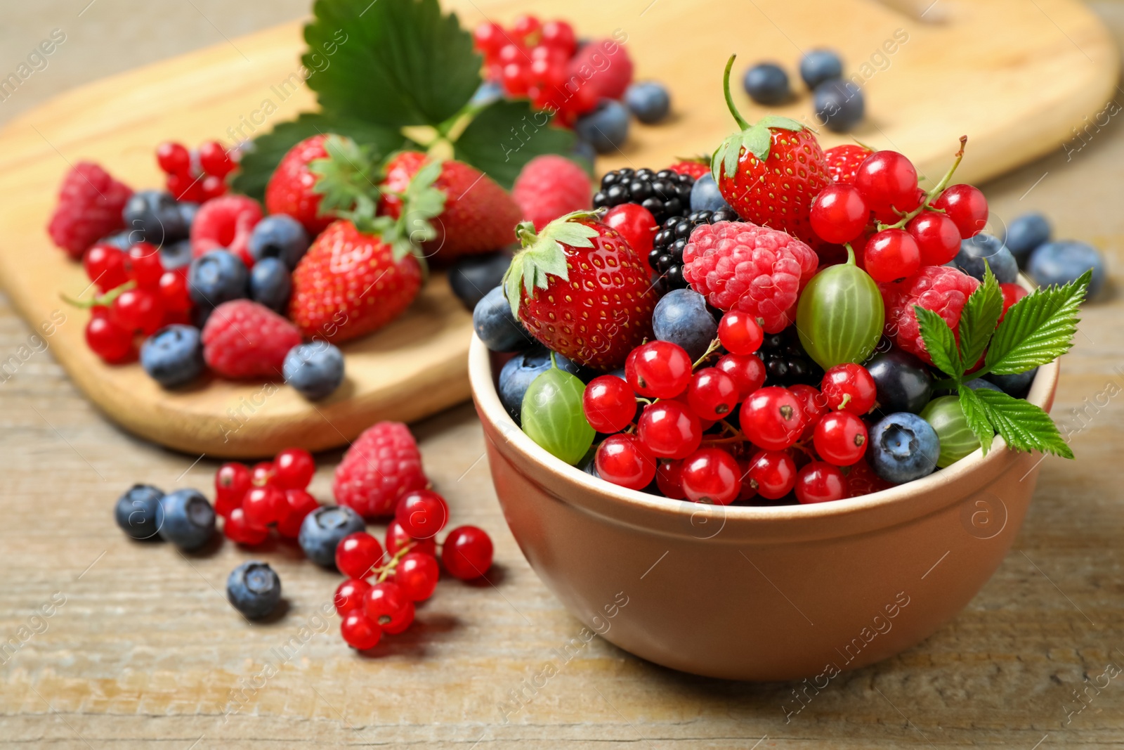 Photo of Mix of different fresh berries in bowl on wooden table