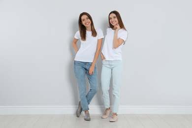 Photo of Young women in stylish jeans near light wall