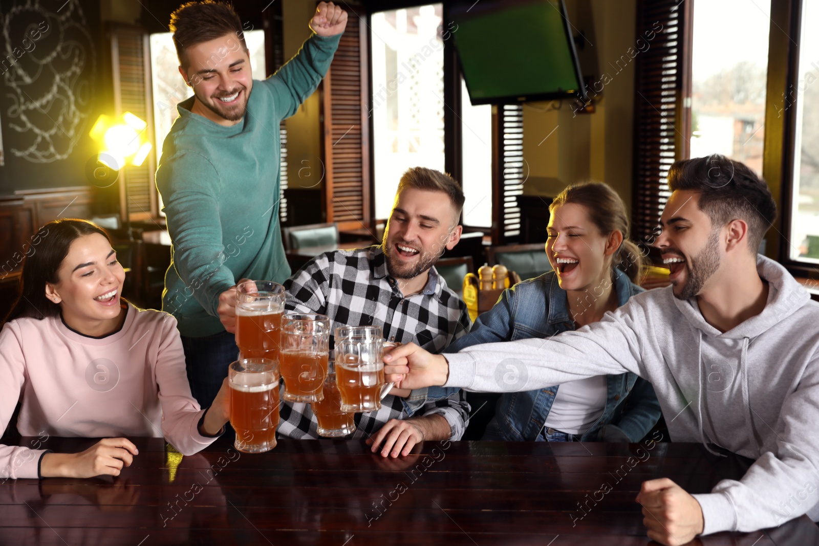 Photo of Group of friends celebrating victory of favorite football team in sport bar