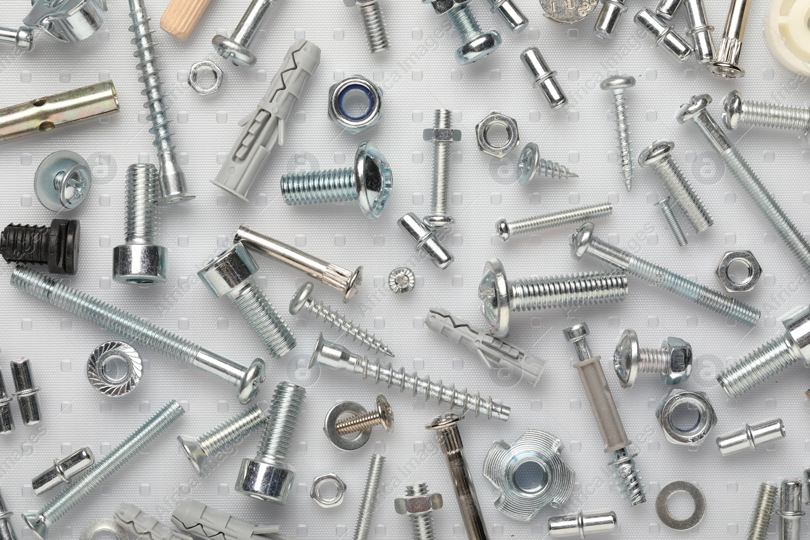 Photo of Many different fasteners on plastic surface, flat lay