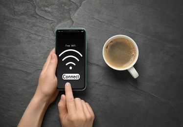 Image of Man connecting to WiFi using mobile phone at black table, top view