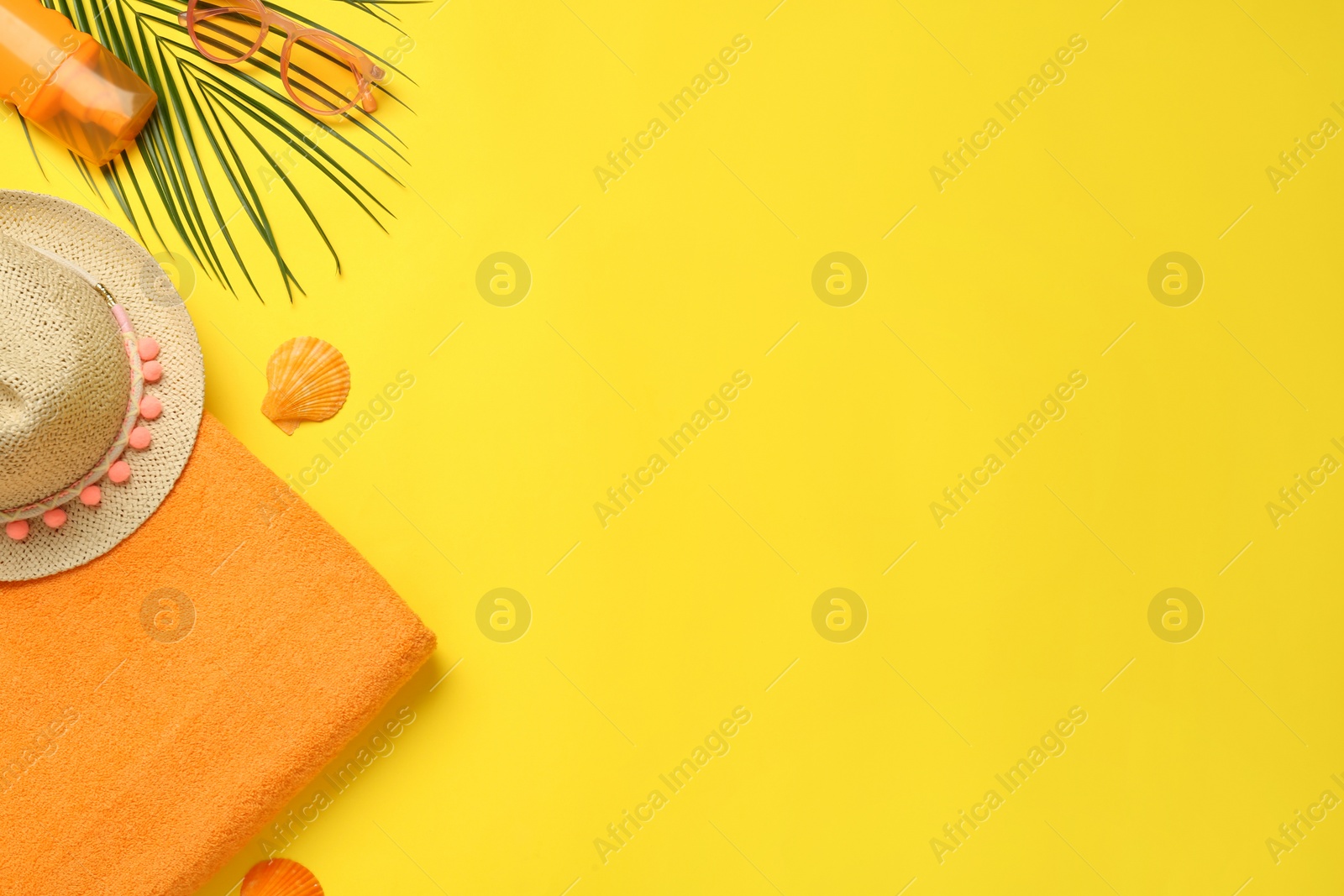 Photo of Beach towel, straw hat, sunglasses and sun protection product on yellow background, flat lay. Space for text