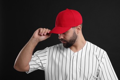 Photo of Man in stylish red baseball cap on black background