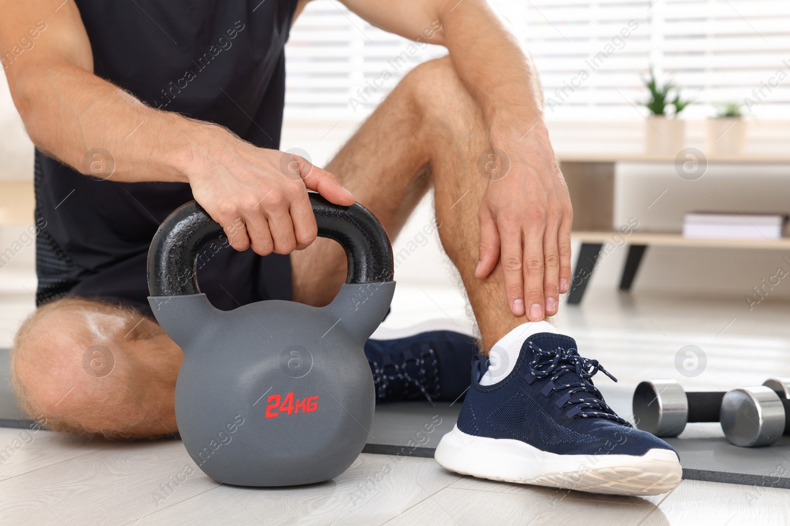 Photo of Man with kettlebell on floor at home, closeup