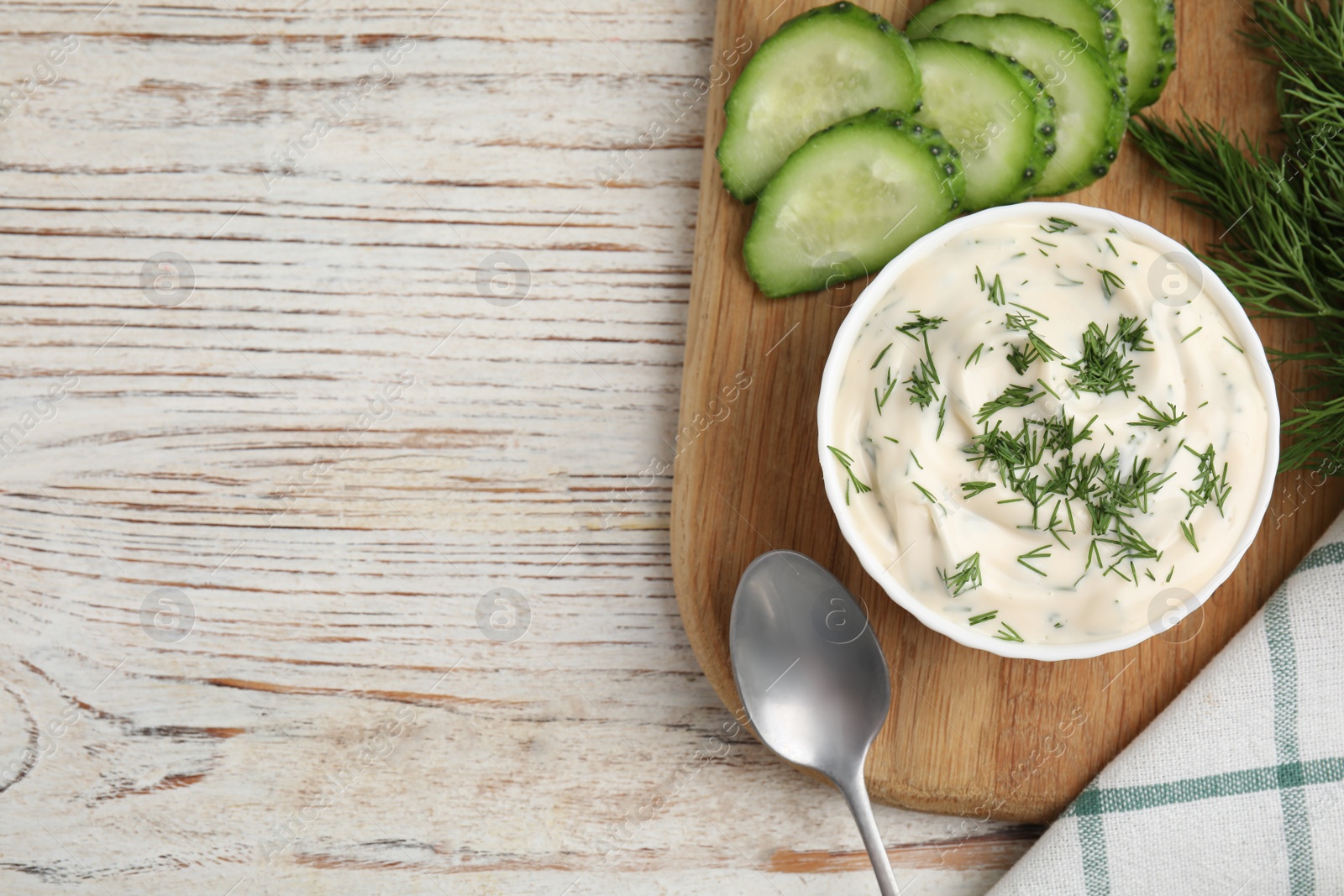 Photo of Tasty creamy dill sauce and ingredients on white wooden table, flat lay. Space for text