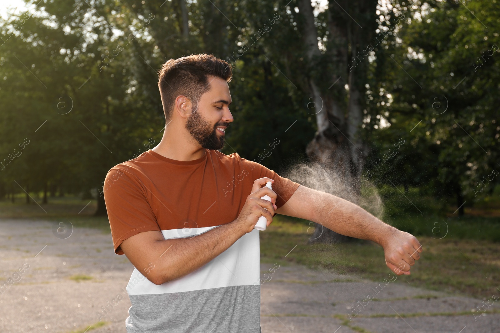 Photo of Man applying insect repellent on arm in park. Tick bites prevention