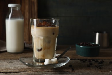 Photo of Glass of delicious iced coffee with milk on wooden table. Space for text